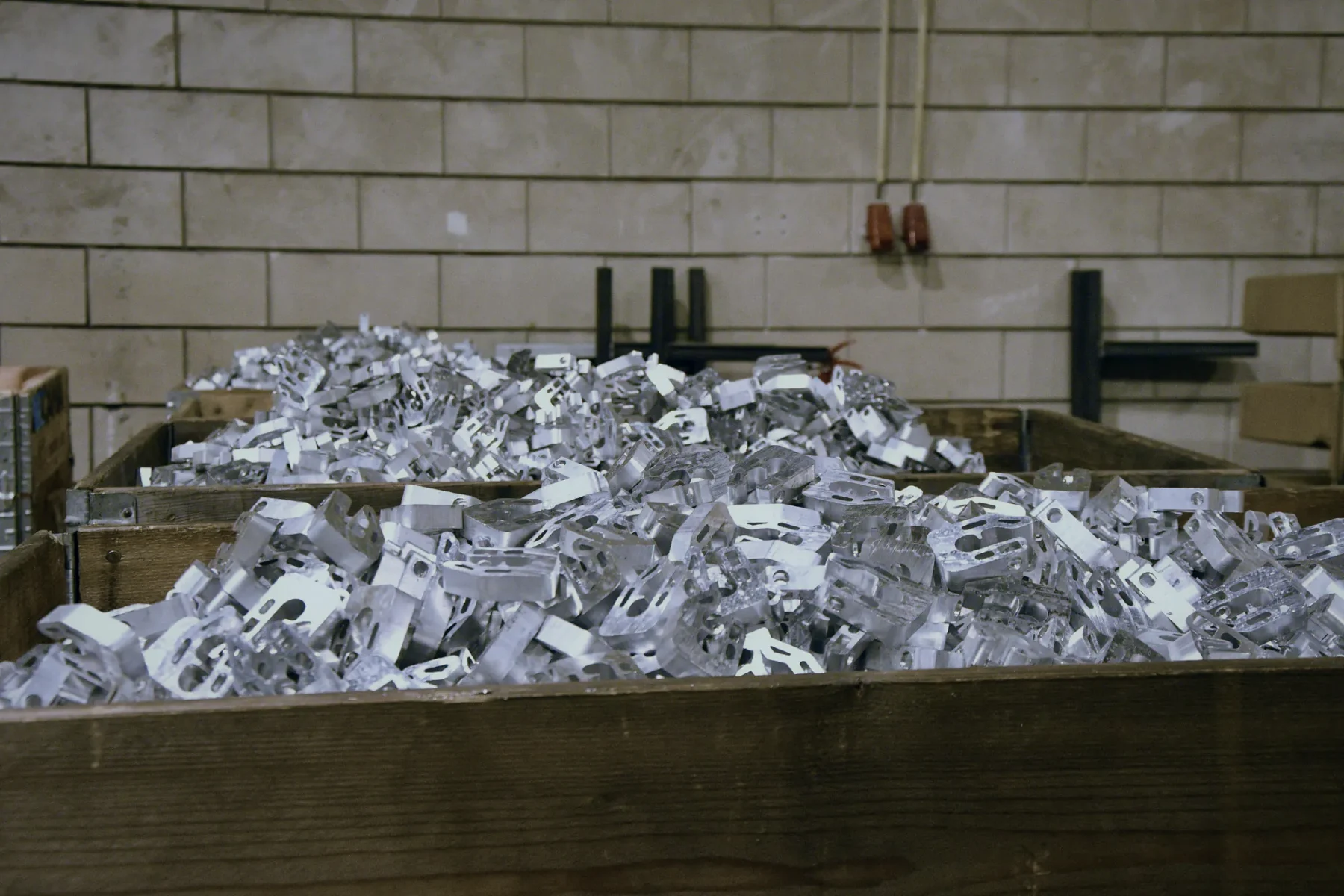 Kisten vol gestanste aluminium onderdelen uit een lopende serie bij HB Metaalbewerking